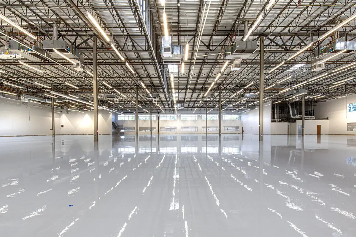 High-gloss light gray epoxy floor reflecting overhead lights in an empty commercial building