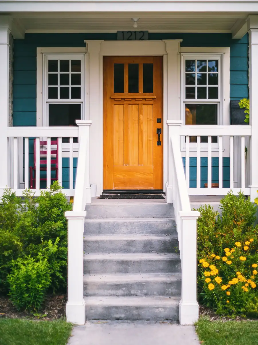 Six gray concrete steps with white railings leading up to a covered front porch